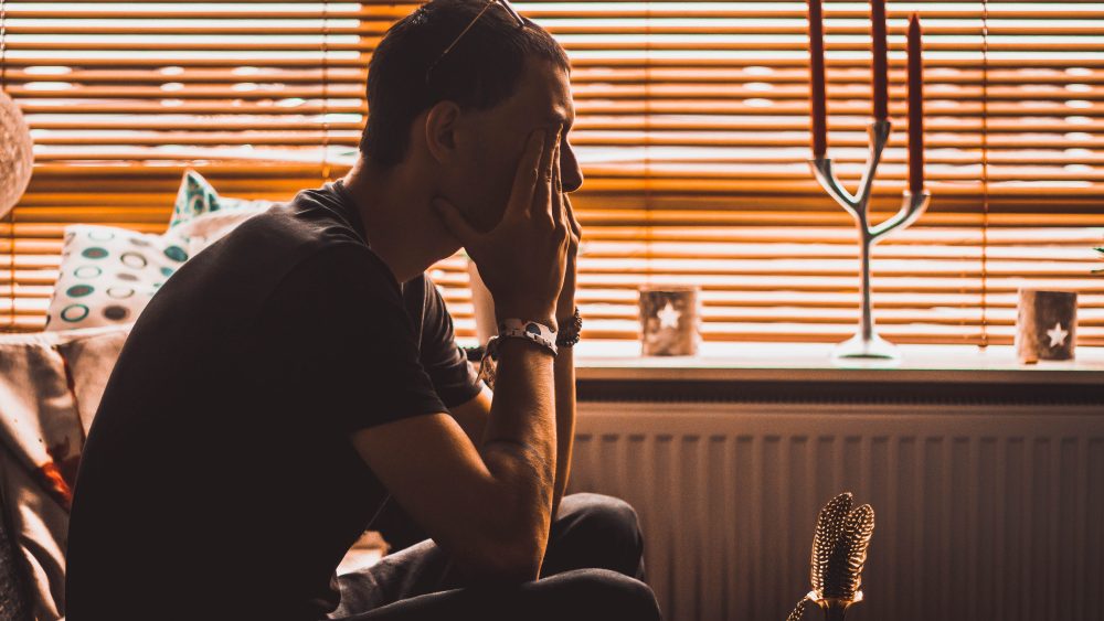 Ung man sitter med ansiktet i händerna.